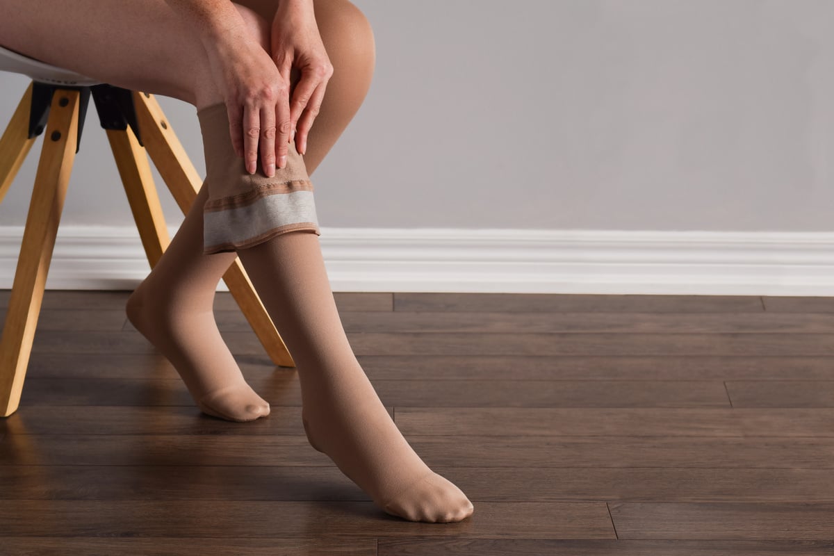 Woman is putting on lymphedema compression stockings